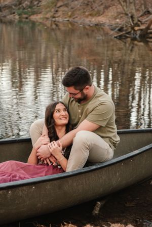 A couple shares an intimate moment while sitting in a canoe on a peaceful lake.