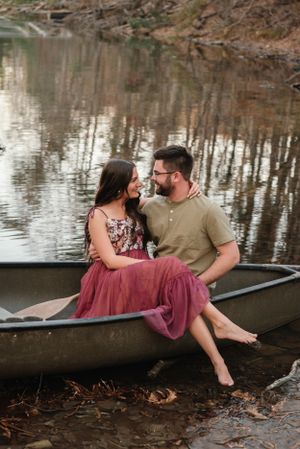 Romantic couple sitting together in canoe sharing intimate moment by peaceful water.