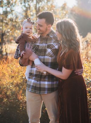 A tender family moment captured in golden sunlight with coordinated plaid and brown outfits.