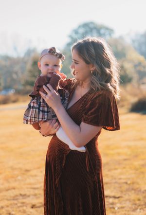 A tender moment between parent and baby in coordinating brown and plaid outfits at sunset.