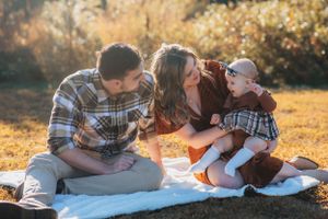 Family picnic scene on white blanket during golden hour in autumn.