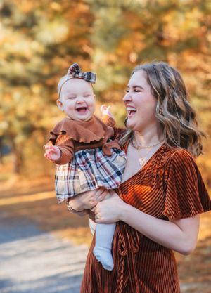 Joyful moment between parent and baby both laughing together outdoors during golden hour.