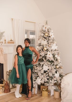 Four festive holiday photos show coordinating emerald green dresses next to a flocked white Christmas tree with gold decor.