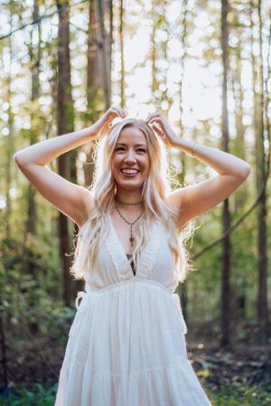 Outdoor portrait in a white dress surrounded by sunlit forest.