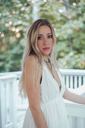 Portrait in a white dress against soft bokeh outdoor background.