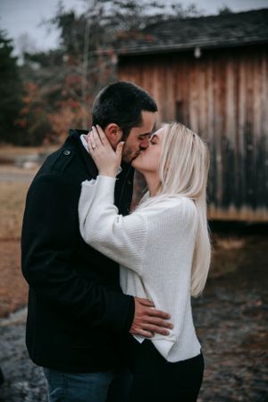 Intimate moment between couple in cozy sweaters by rustic barn.