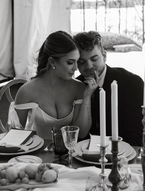 Romantic black and white photo of a couple dining at an elegant table with candlelight and crystal glassware.