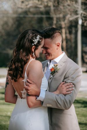 A tender moment between newlyweds in formal attire embracing in an outdoor garden setting.