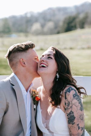 A joyful wedding couple sharing an intimate moment outdoors with the bride wearing a white dress.