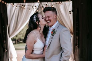 An intimate wedding moment captured under a decorated archway with white drapes.