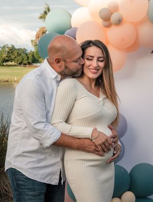 Maternity photoshoot with balloon arch display and waterfront backdrop.
