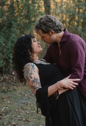 Intimate couple embrace in romantic forest setting with autumn foliage.