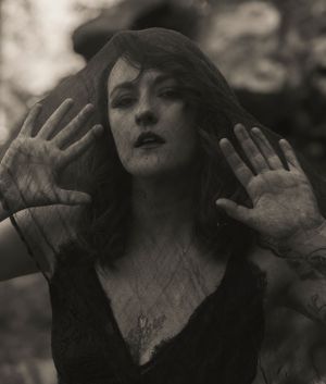 Artistic black and white portrait showing hands pressed against glass with dramatic lighting and shadows.