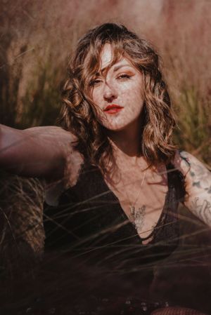 Moody portrait in warm tones featuring dark clothing and natural outdoor lighting.