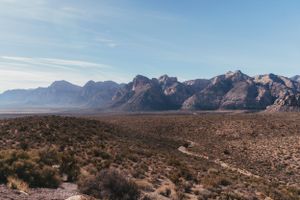 Panoramic view of desert mountain range with winding road through rugged terrain.