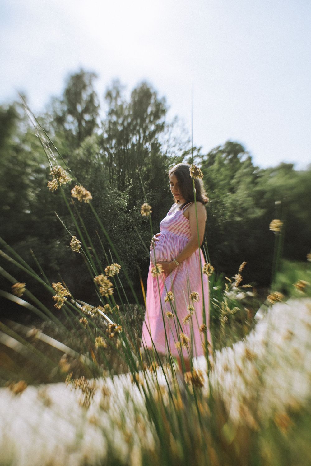 A person in a flowing pink dress stands among tall wildflowers in a meadow.