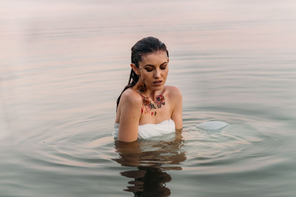 A serene scene of someone bathing in calm waters during sunset.