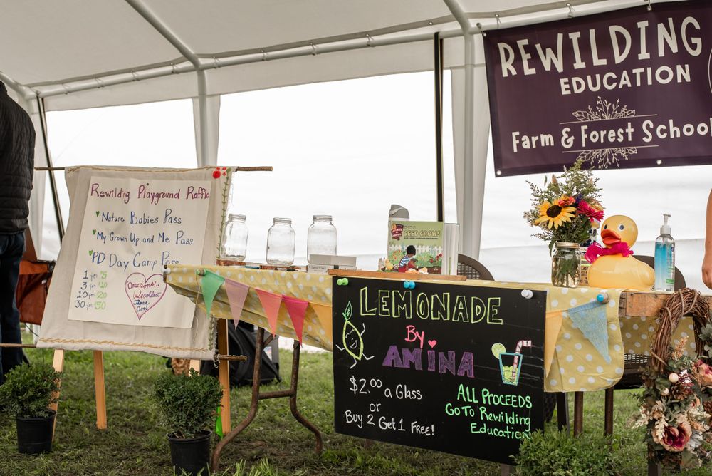 Educational farm school booth with handwritten signs and decorative displays under white tent.