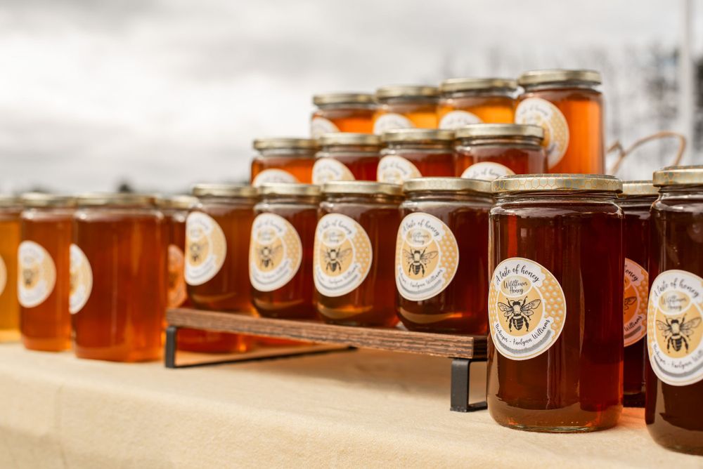 Rows of honey jars with branded labels displayed at market stand.