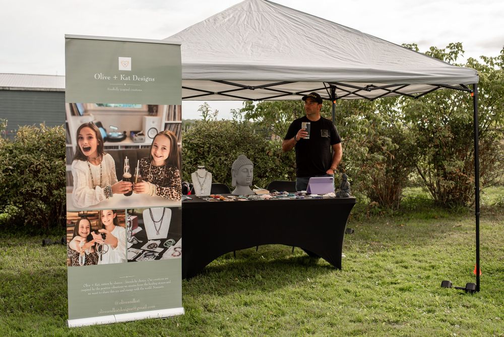 Jewelry vendor booth with banner and display stands at outdoor market.