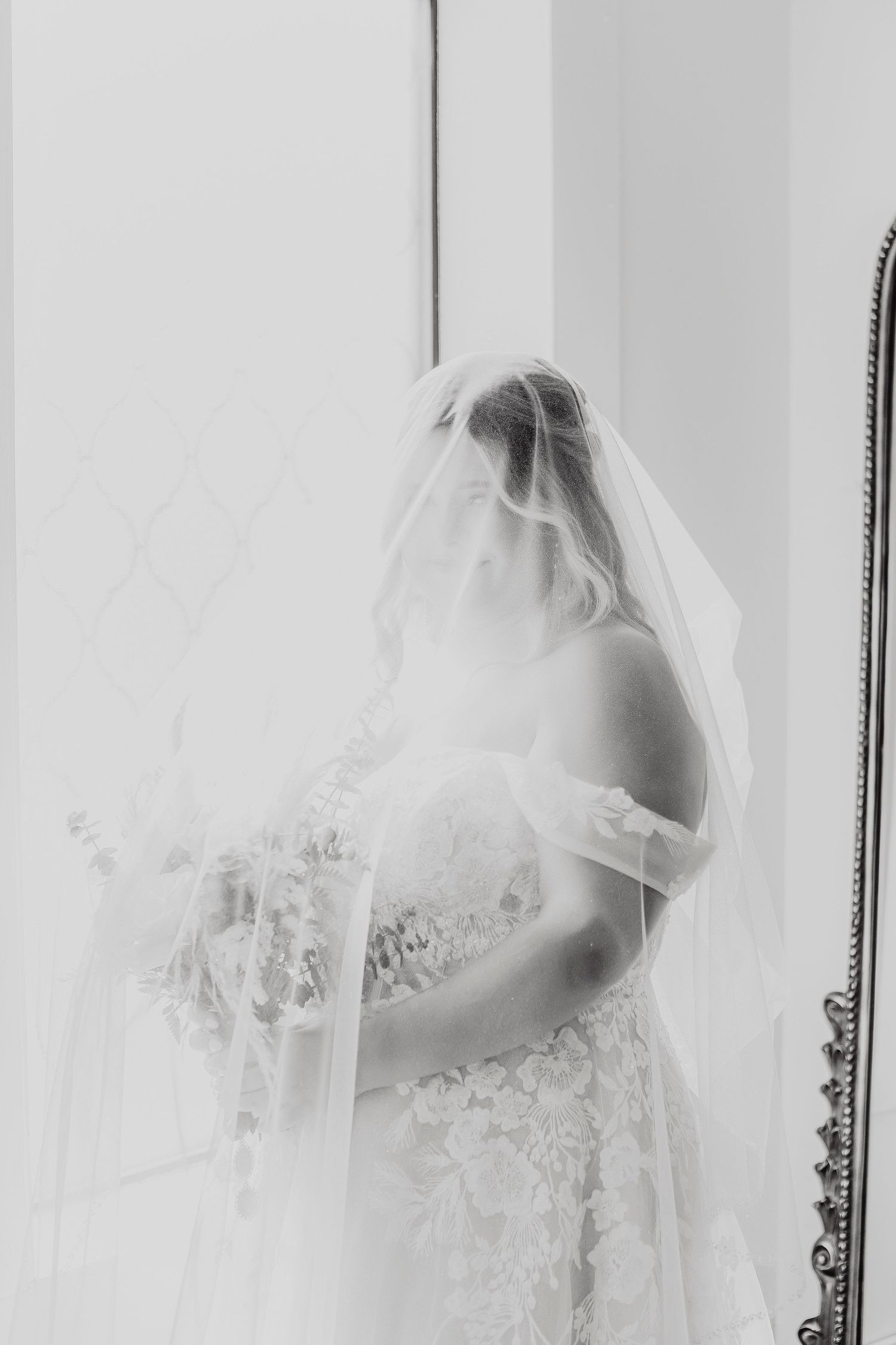 Delicate lace wedding veil details shown in soft white light against a neutral background.