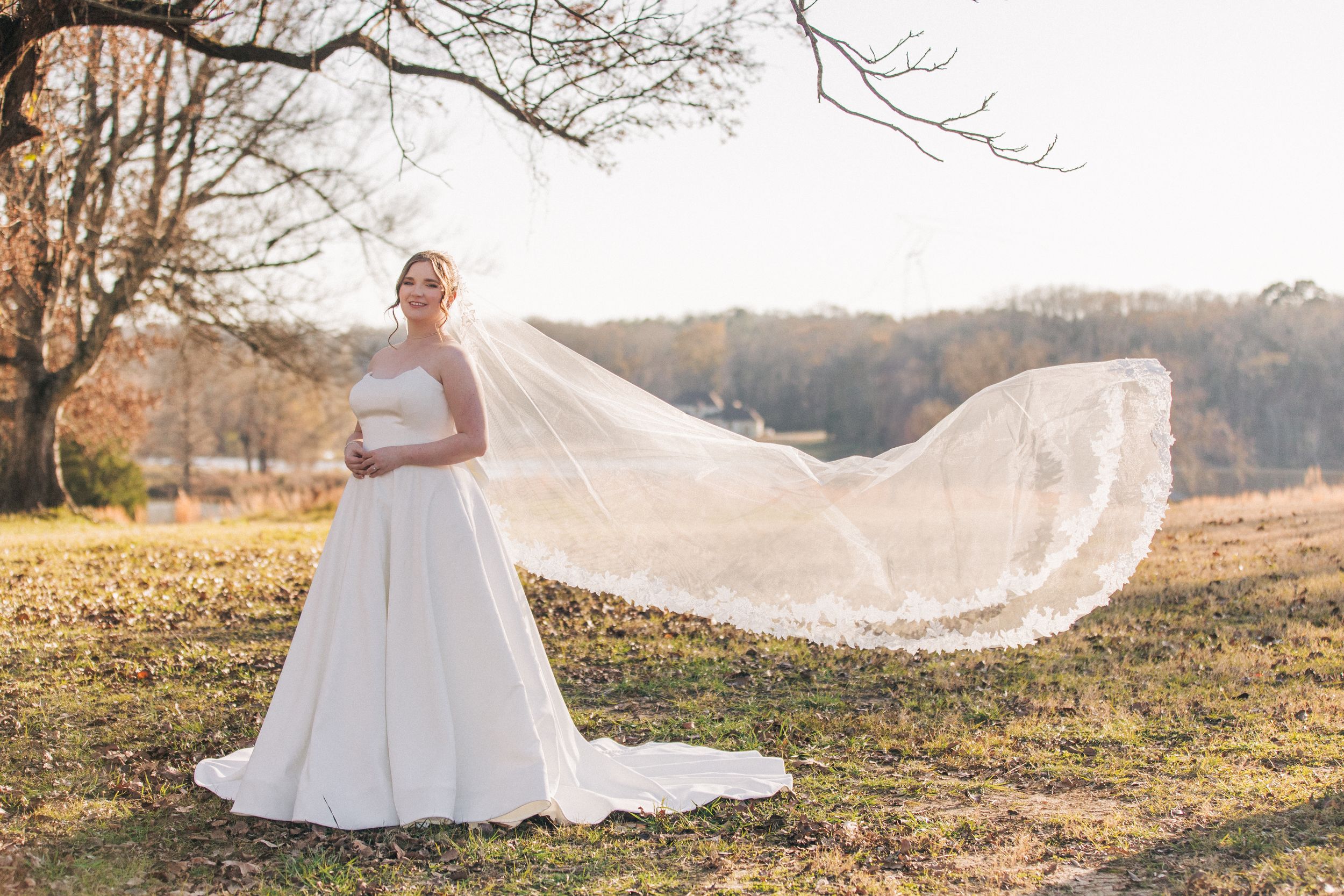 Beautiful wedding portrait in a fall field with flowing lace veil catching the sunlight during golden hour.