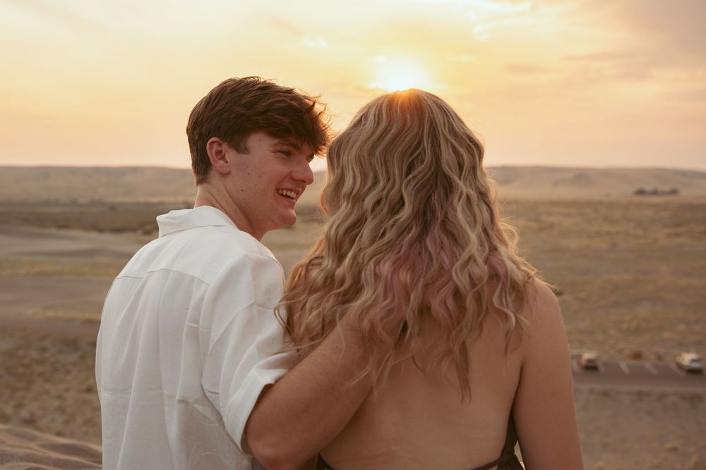 Young couple enjoys sunset view together from elevated vantage point over desert landscape.