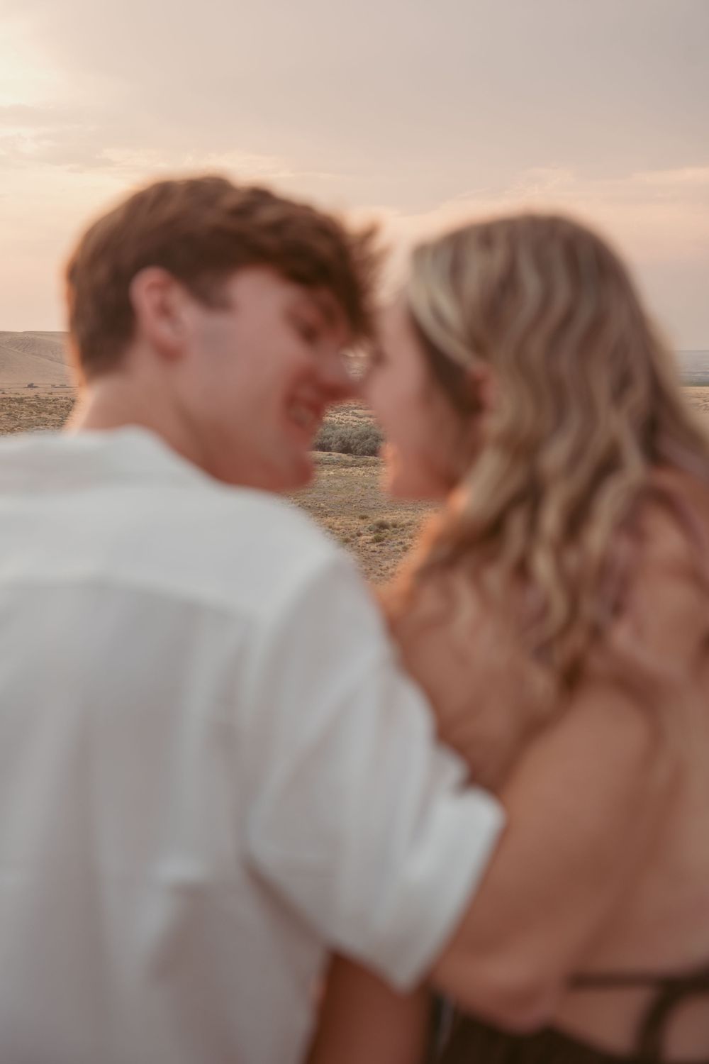 Couple sharing an intimate moment on a beach at sunset with a dreamy blurred effect.
