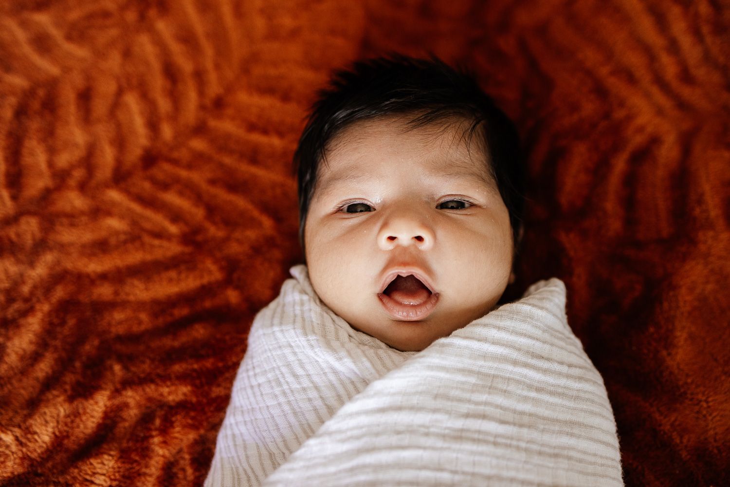 Newborn baby smiles at the camera during her in-home newborn session in San Jose