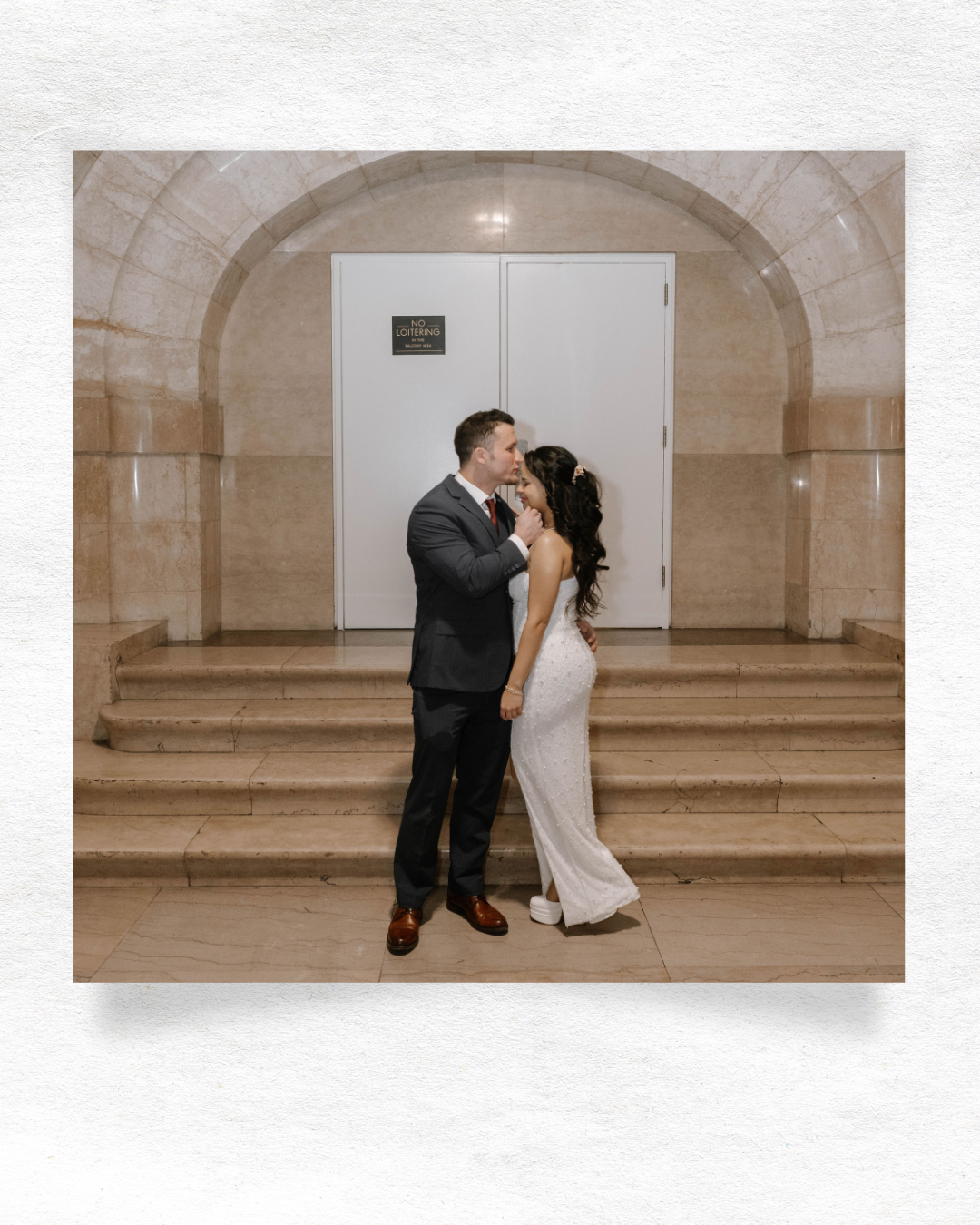 Couple sharing a romantic moment in a vintage stone-walled venue with arched architecture.