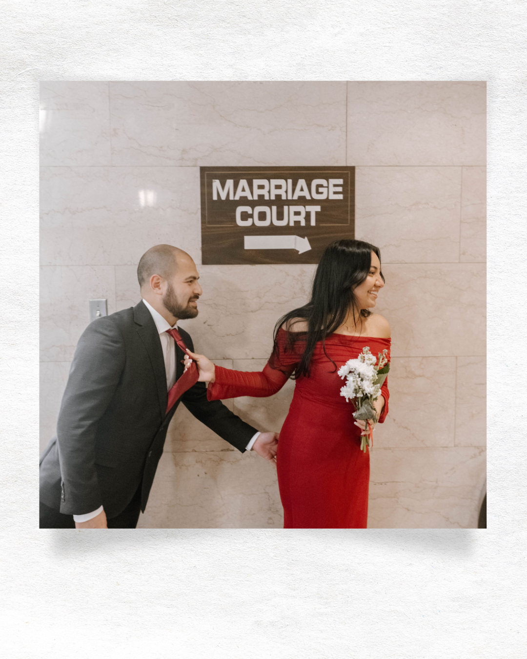 A couple in formal attire walks together down an indoor hallway with a marriage court sign above.