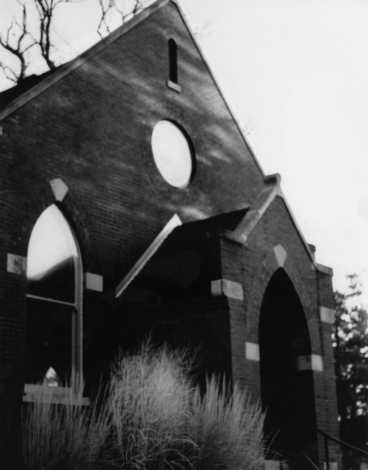 Black and white architectural detail of an old church's arched windows and brick facade in dramatic lighting.