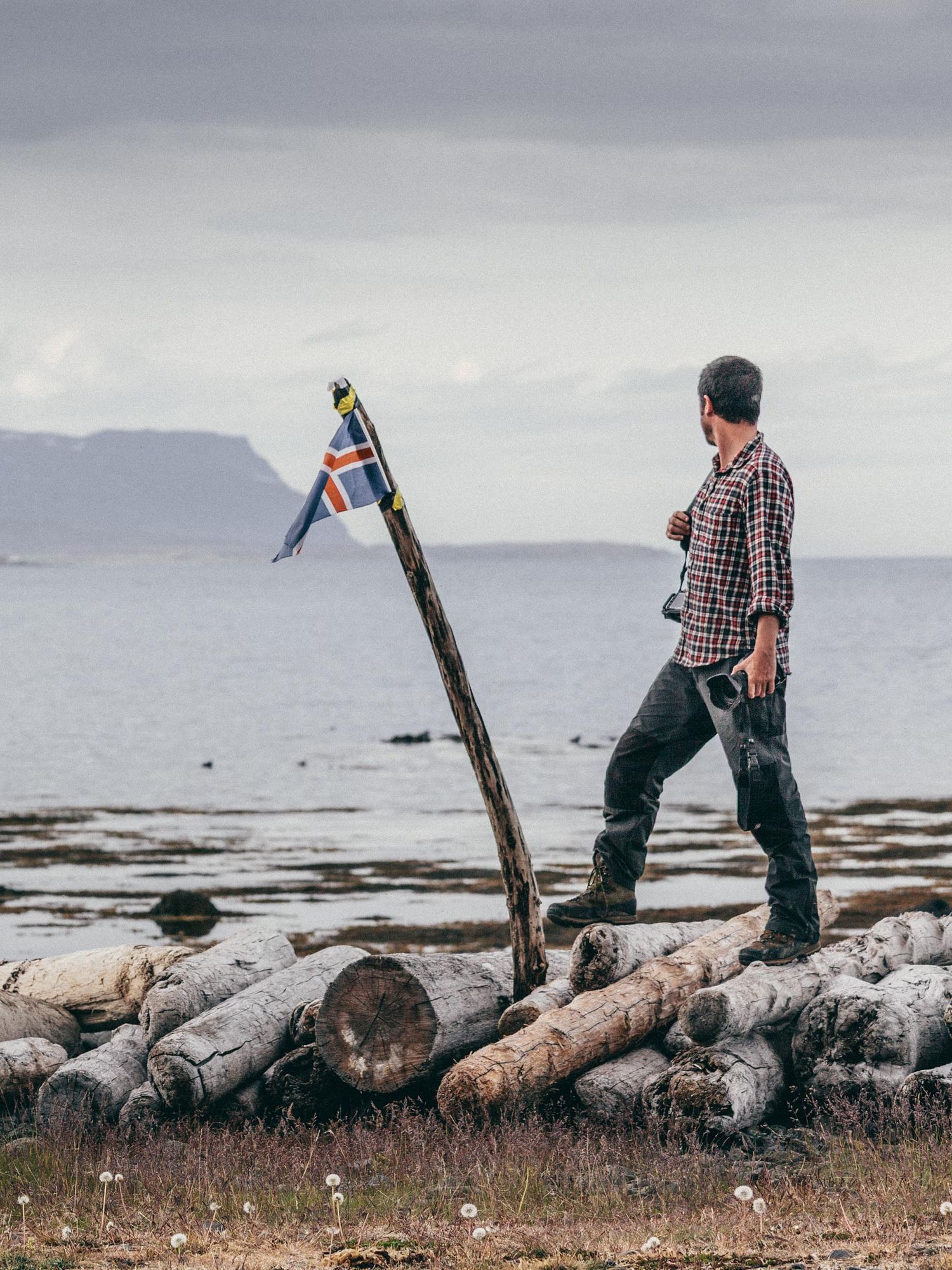 Michael LEVY in Iceland Westfjords with camera equipment by a serene lake under moody storm clouds.