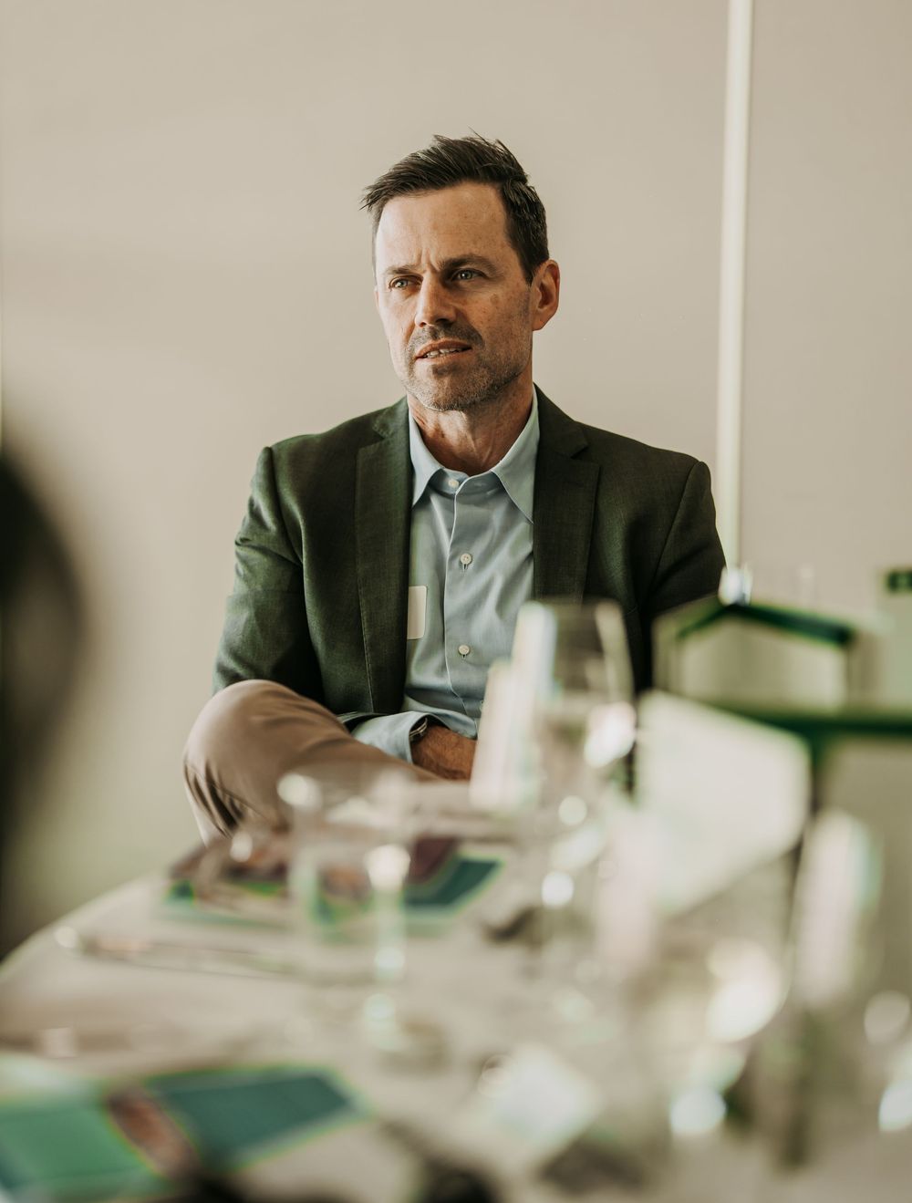 A person in a dark suit jacket sits at a conference table during a business meeting.