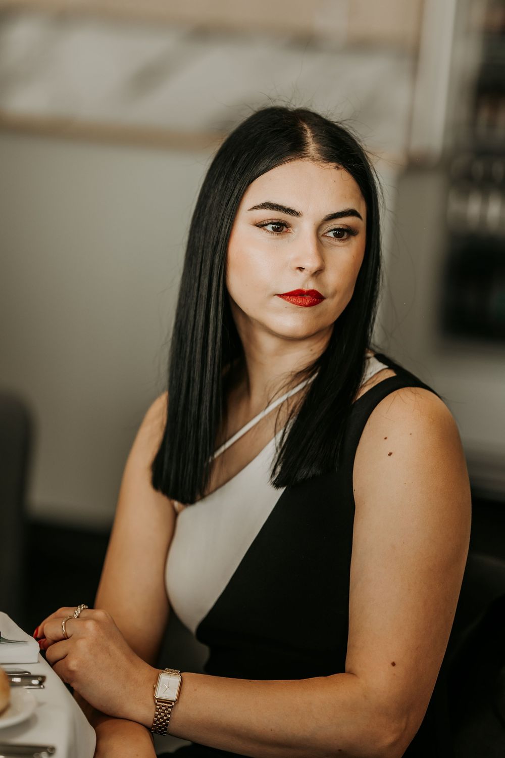 Professional studio portraits with red lipstick and black attire against neutral background in moody lighting.