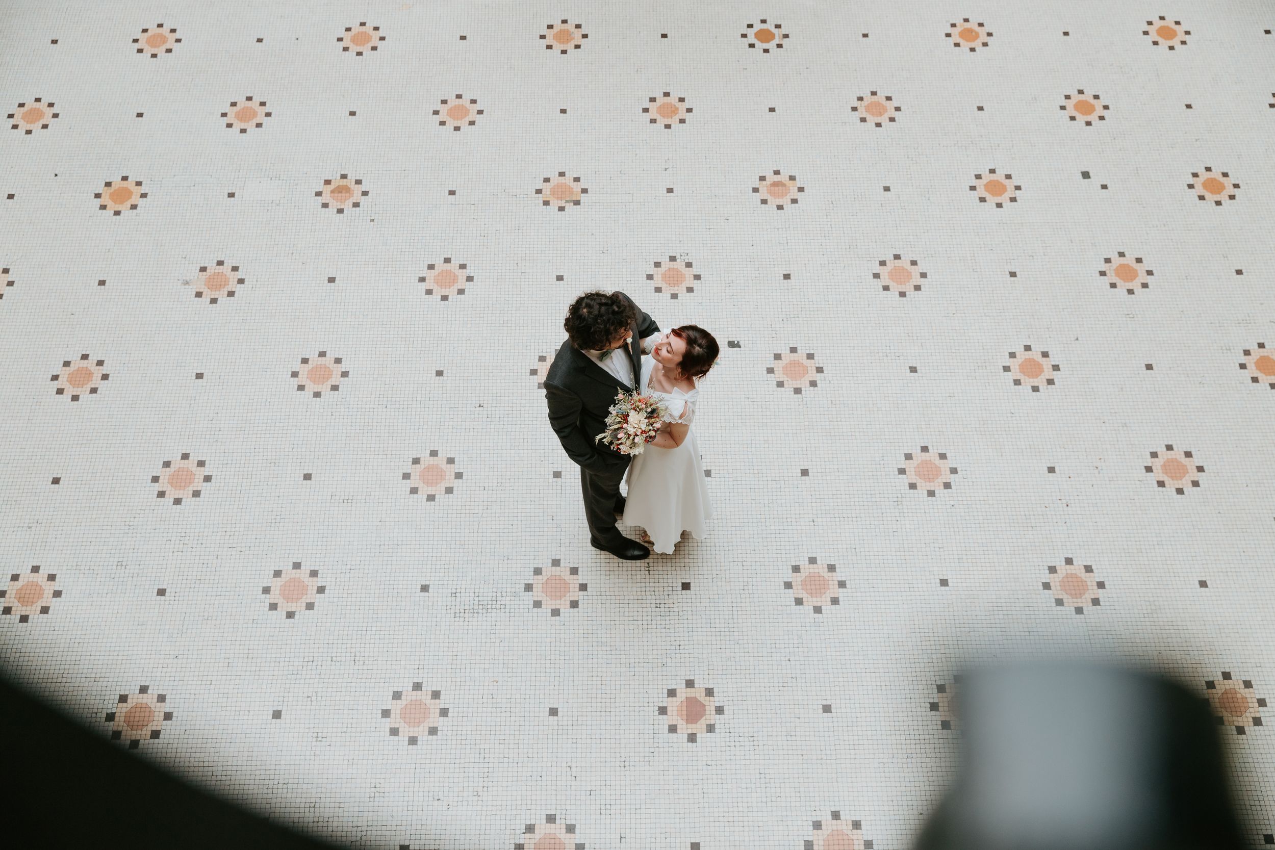 Three black and white photos against a wallpapered backdrop with small orange flower pattern show a couple's candid moments.