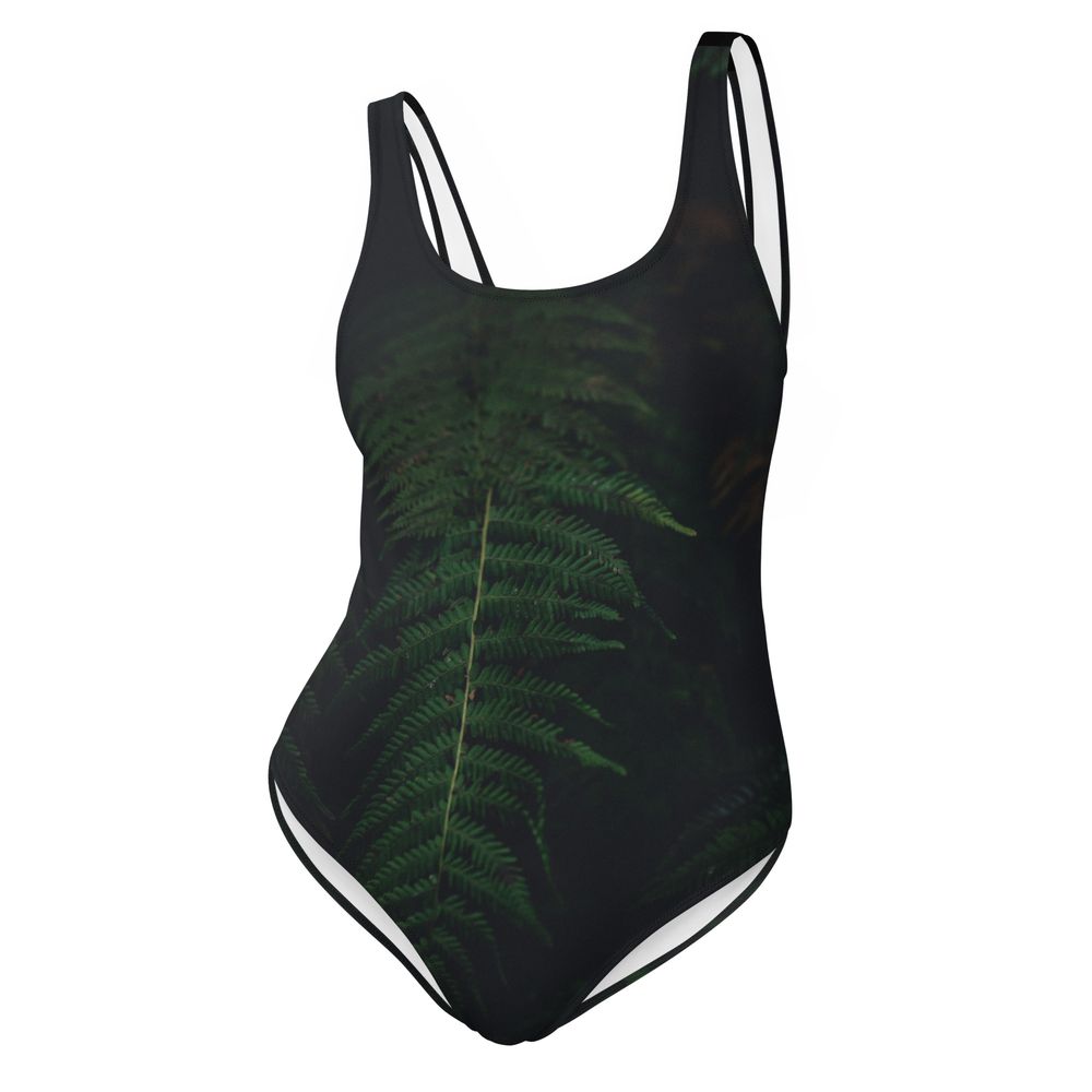 Black one-piece swimsuit featuring an elegant green fern leaf pattern design with white trim detailing.