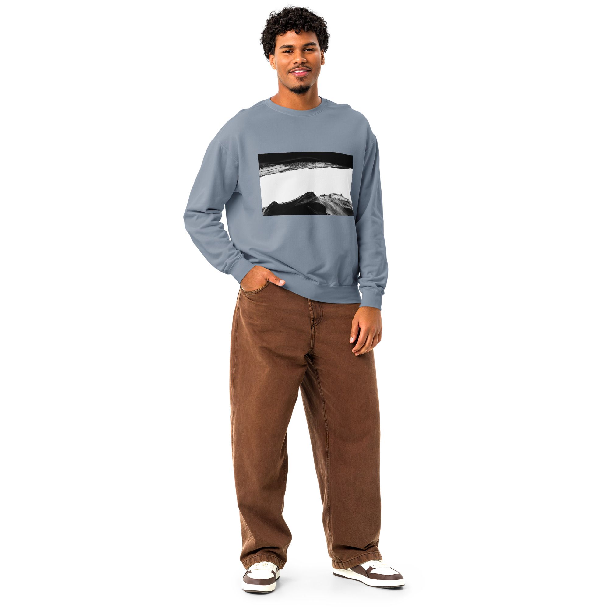 Person wearing a light blue graphic sweatshirt with brown wide-leg pants and white sneakers in casual pose.