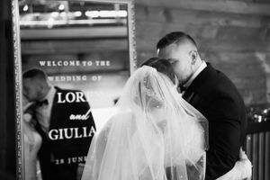 Black and white photo of newlyweds sharing an intimate kiss at their wedding reception.