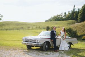 Classic vintage car wedding photo shoot in a scenic countryside setting.