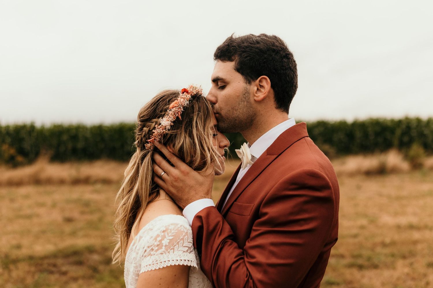 Romantic outdoor portrait in rustic setting with terracotta suit and floral crown.