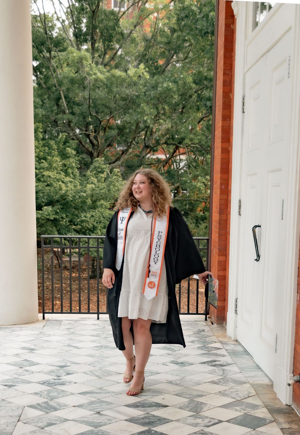 Black and white series showing someone in a casual outfit walking along a white columned porch with greenery in background.