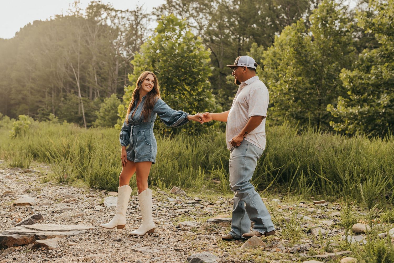 Two people in casual wear walk together on a rocky path surrounded by greenery on a sunny afternoon in Broken Bow, Ok.