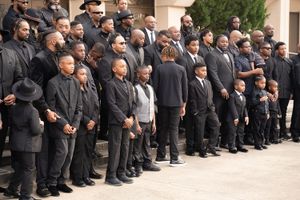 Group photo of people wearing black formal attire standing together on steps.
