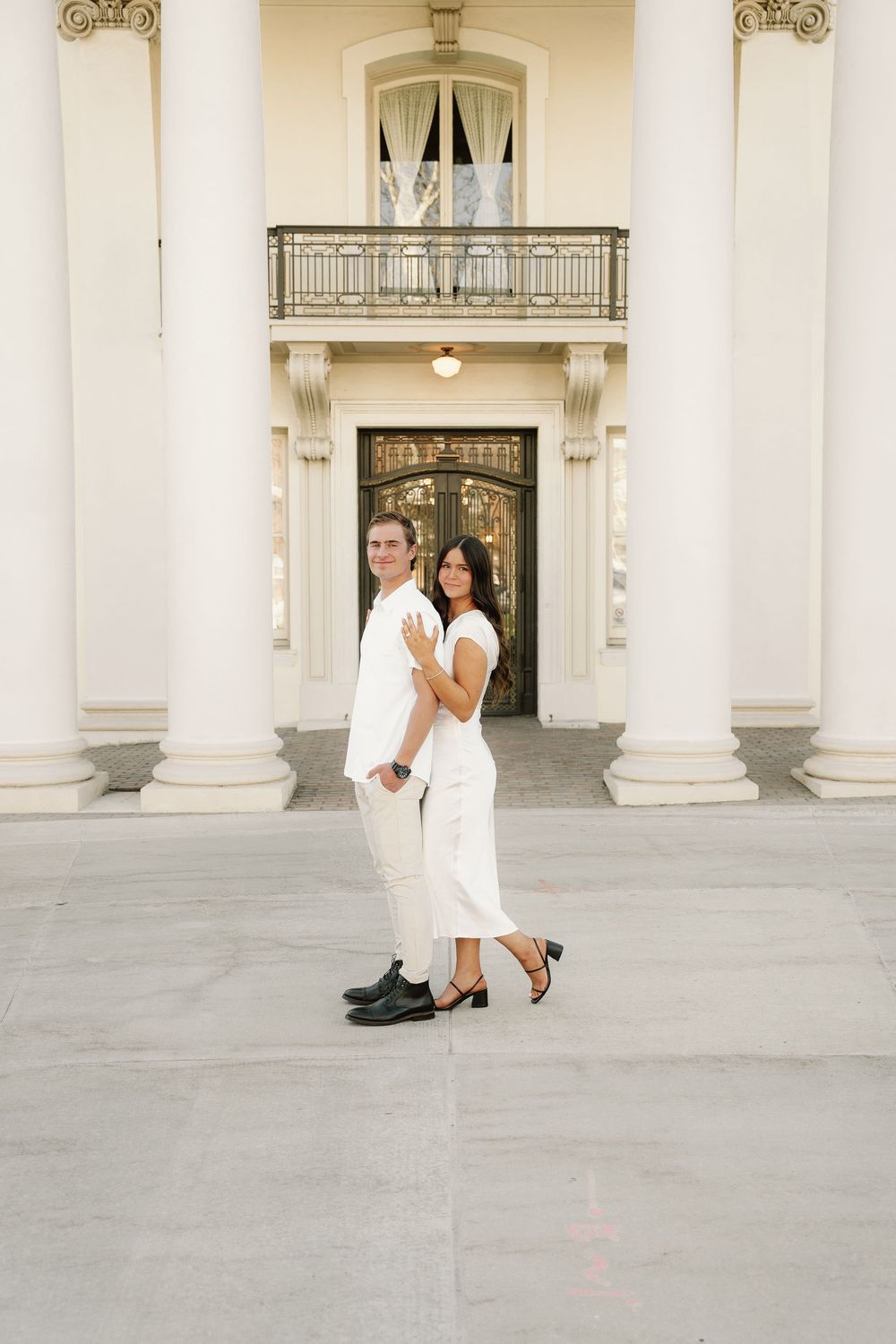 A series of tender moments captured between a couple in white outside a grand columned building.