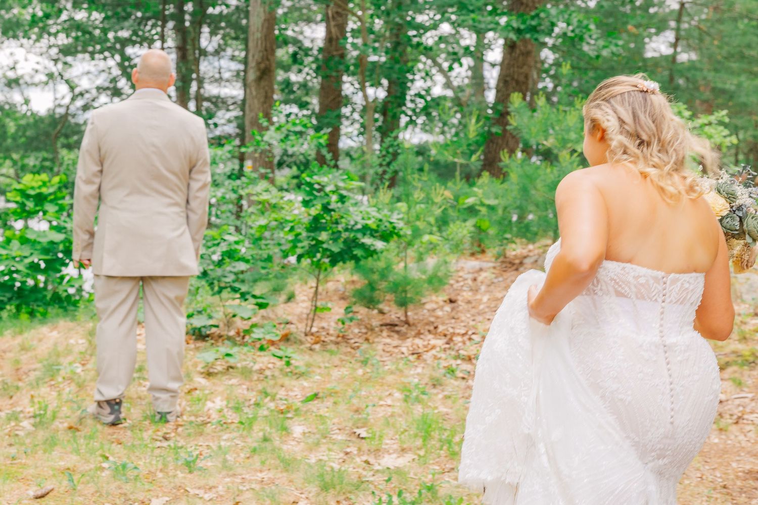 A first look moment captured between the bride and groom outdoors in a serene forest setting.
