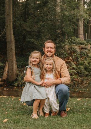 A heartwarming family moment captured in a natural forest setting with tall trees.