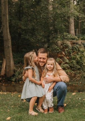 An intimate family portrait showing tender moments in a wooded outdoor setting.