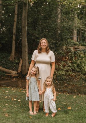 A maternity portrait with children taken in a serene forest setting during autumn.