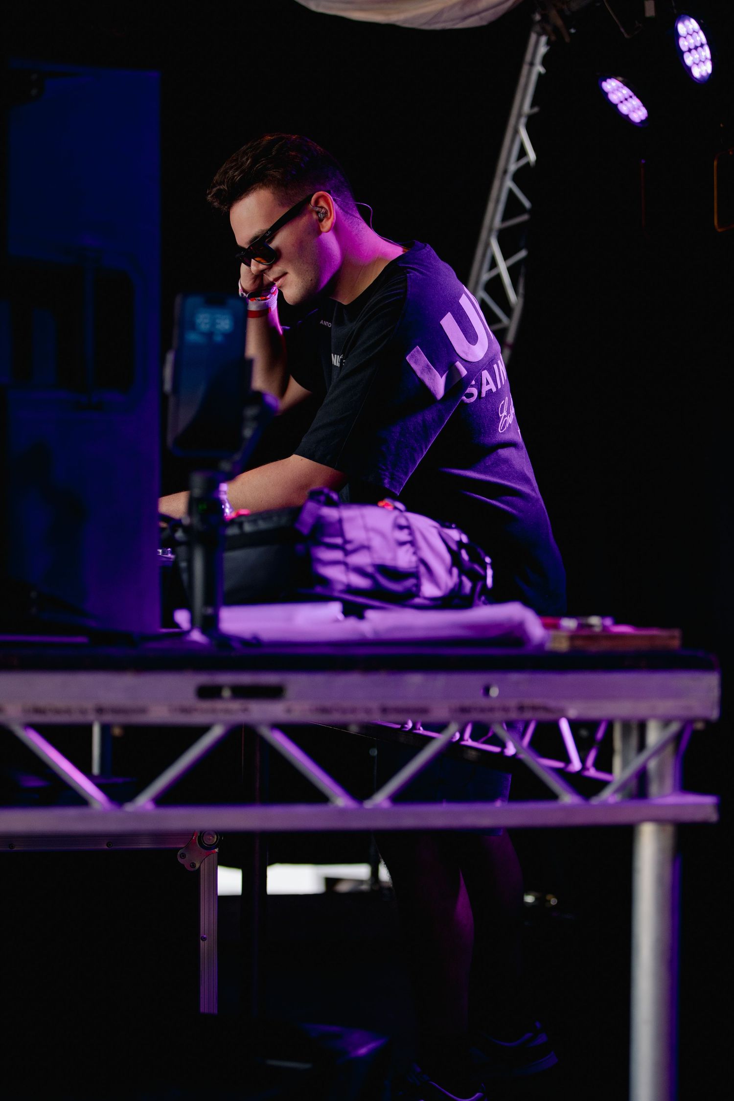 Person working at illuminated desk setup with purple lighting in dark environment.